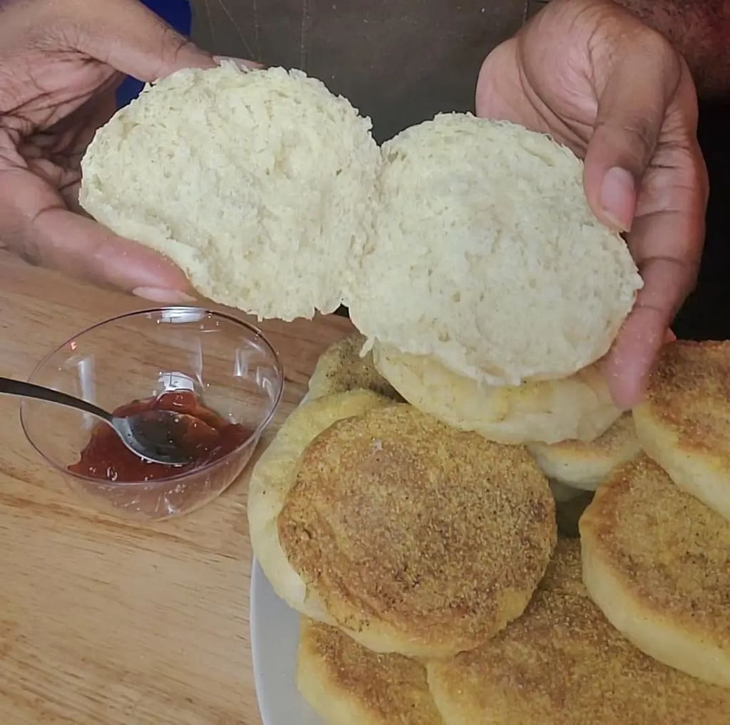 This image show a split english muffin as described by this blog post on lesliecooks.com. You will also see a pile of English muffins and a small bowl of red strawberry jam.