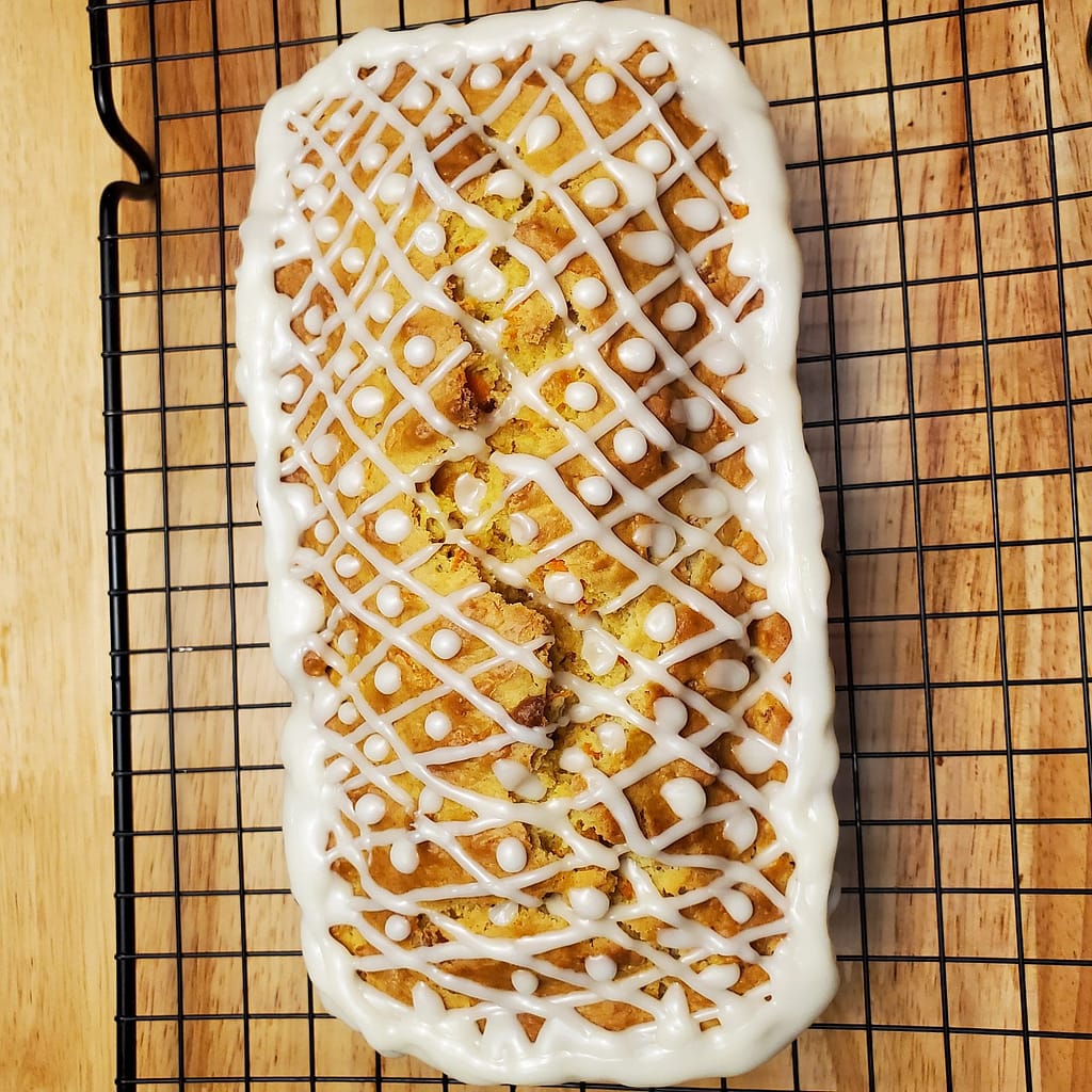 This image depicts apricot carrot bread baked and iced on a colling wrack.