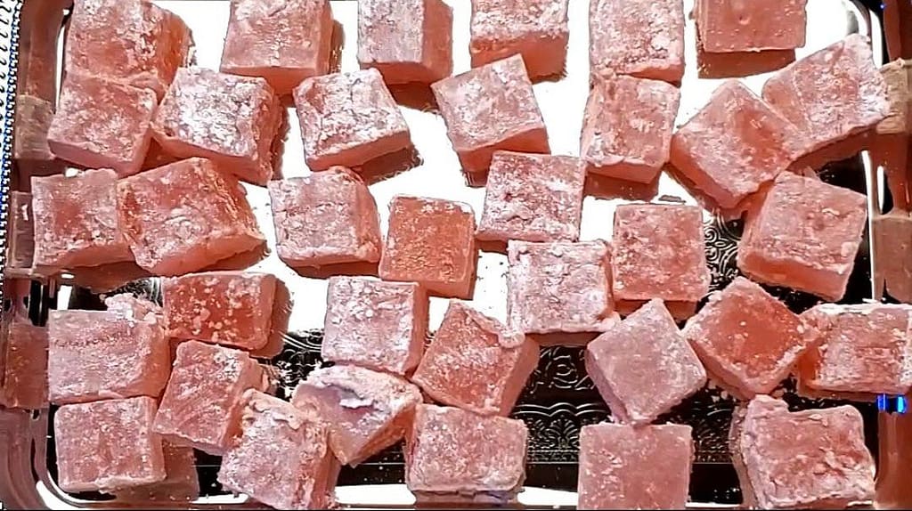This image show pink cubes of Turkish delight served delicately on a silver serving pan. This is shot from a top down angle.