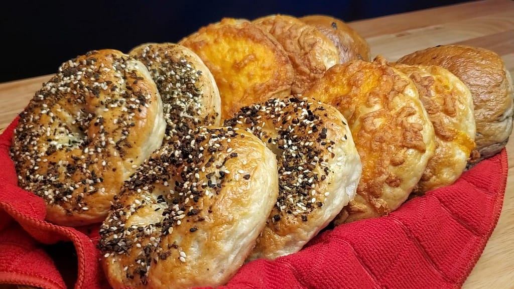 This image depicts bagels in a bread basket with a red towel.
