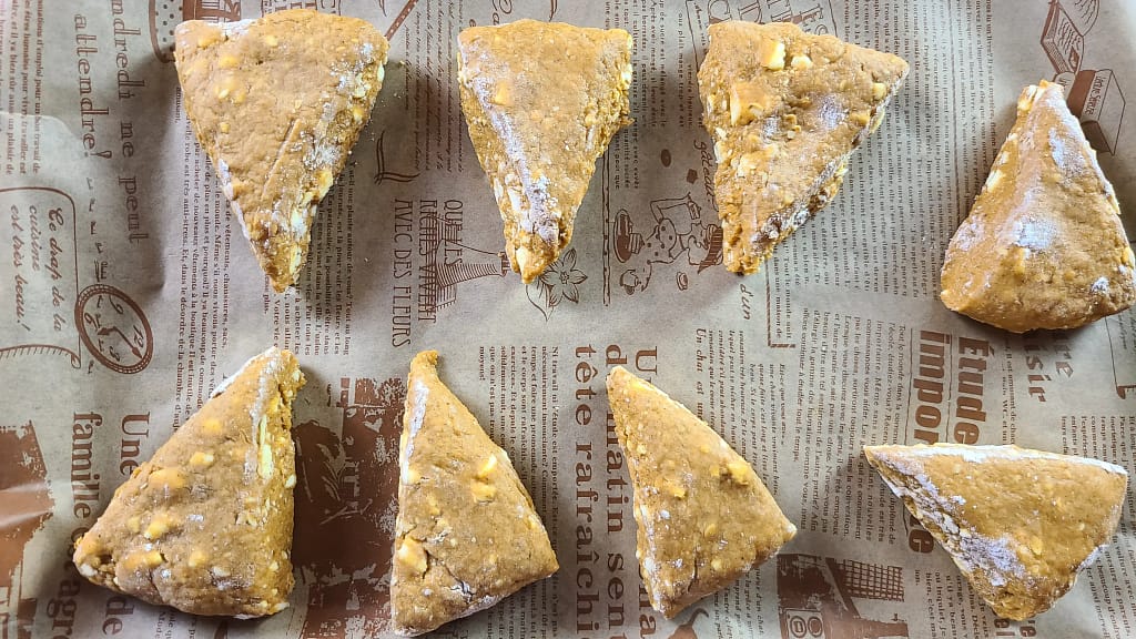 This image depicts unbaked pumpkin scones, cut into triangles.