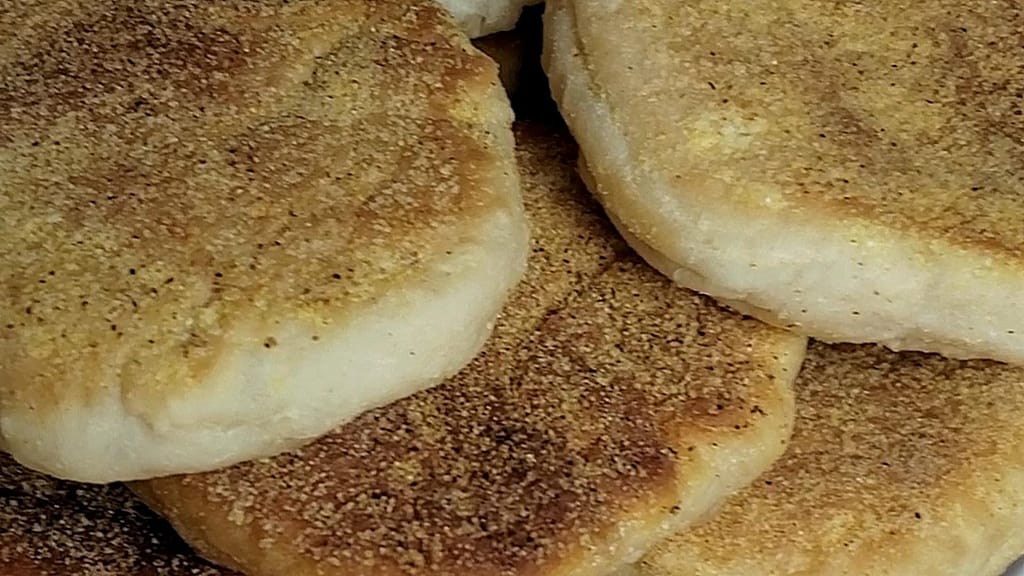 This image depicts english muffins as described by this english muffin recipe arranged in a stack on a white plate.