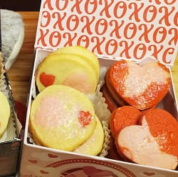 This image depicts the finish heart shaped ice box cookies that this recipe will help you create. They are pink and red cookies. One is round with pin and red hearts. The other is heart shaped with pink and red marbling.