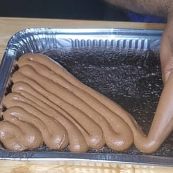 This image depicts chocolate cream cheese frosting being piped onto moist chocolate cake. as described on this blog post on lesliecooks.com.