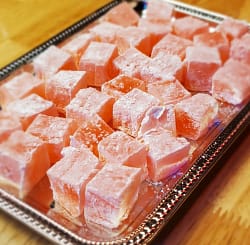 This image show pink cubes of Turkish delight served delicately on a silver serving pan.