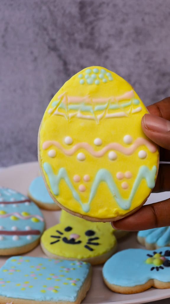 This image shows painted no spread sugar cookies. It is painted yellow with pale blue accents.