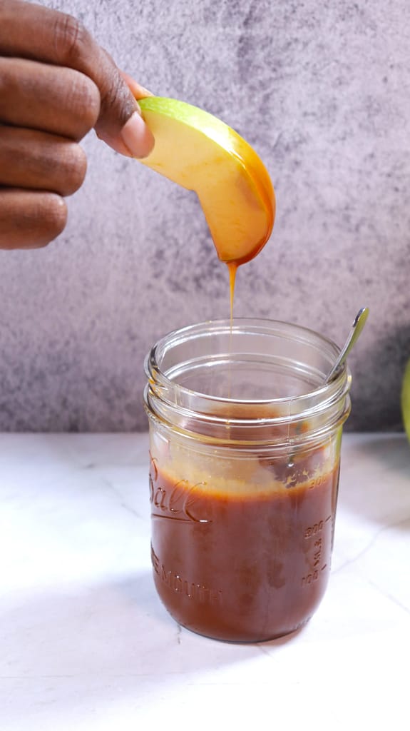 This image shows a pieces green apple dipped into golden brown caramel sauce.