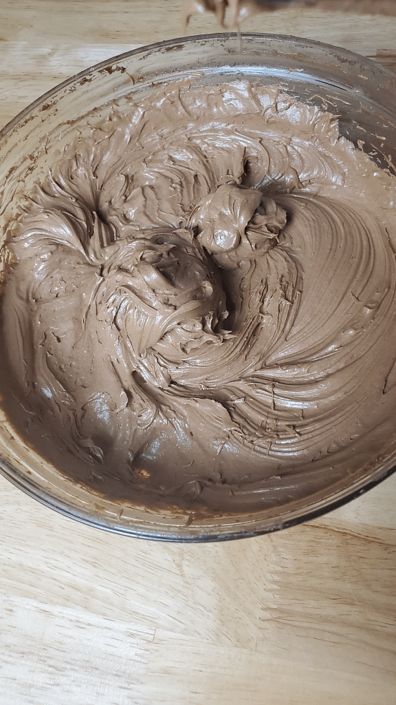 This image depicts chocolate frosting after it has been mixed together and is smooth.