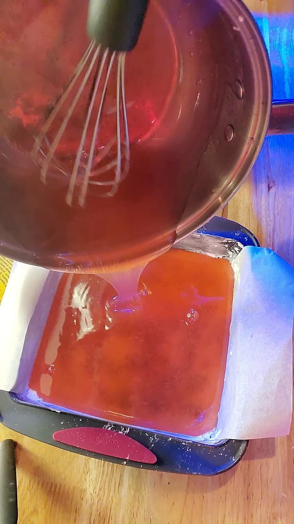 This image depicts hot turkish delight being poured in a powdered sugar coated baking pan to cool.