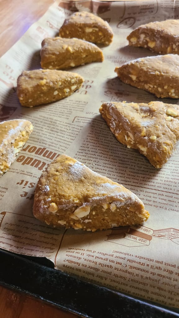 This image depicts cut pumpkin scones on a baking sheet with decorative parchment paper. Scones are unbaked.