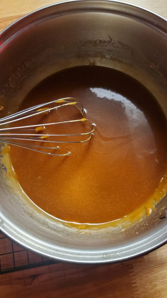 Caramel Sauce being stirred with a whisk in steal sauce pan.