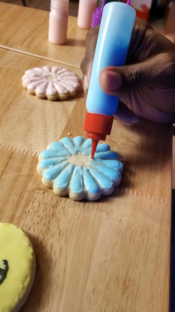 This image show piping a blue flower using piping bottles.