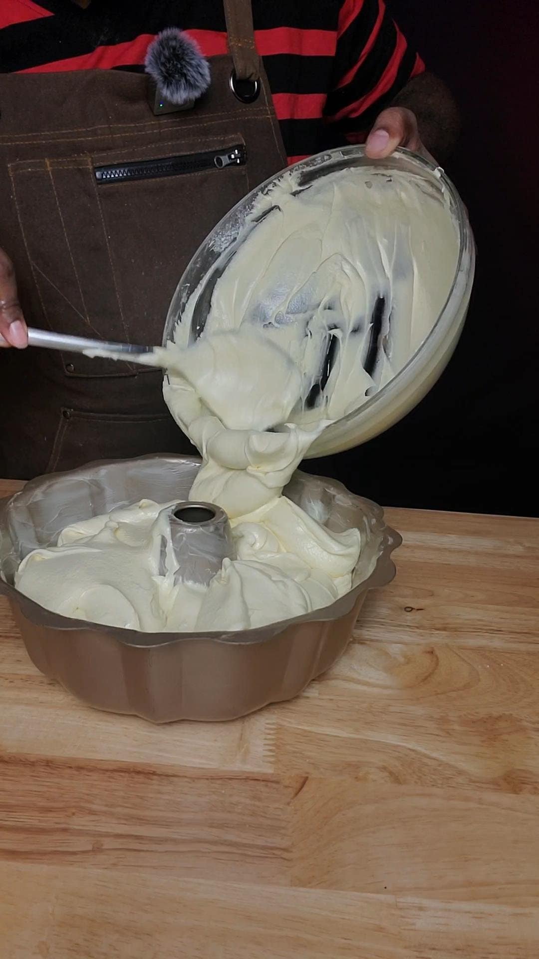 This image shows pound cake batter being poured into a bundt cake pan. Cake batter is pale yellow and very thick.