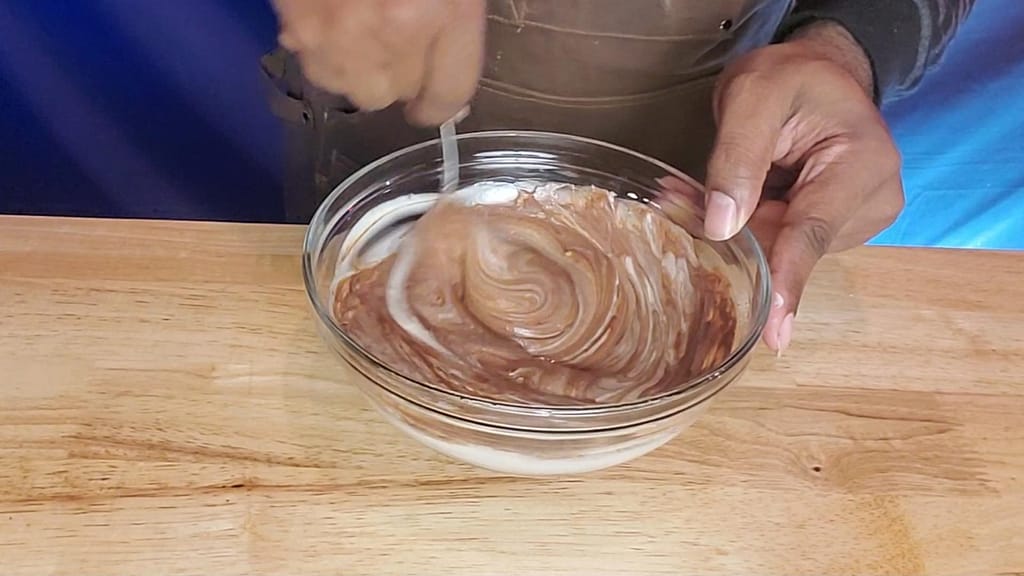 This image depicts Leslie mixing the cheesecake base into the melted Semi-sweet chocolate.