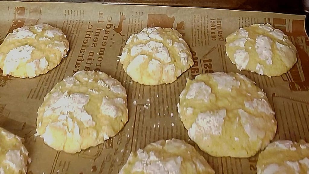 This image depicts the fully baked coconut lemon lime cookies as describe by this blog post on lesliecooks.com.  They are baked on some decorative parchment paper. 