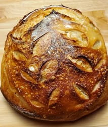 This picture depicts a boule of sourdough bread. It shows the results of follow the recipe on this page. The boule is golden brown with a nice crust.