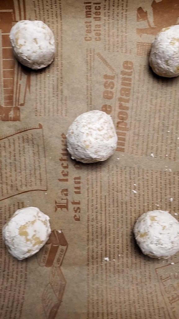 This image depicts coconut lemon lime cookie dough on a cookie sheet lined with decorative parchment paper.