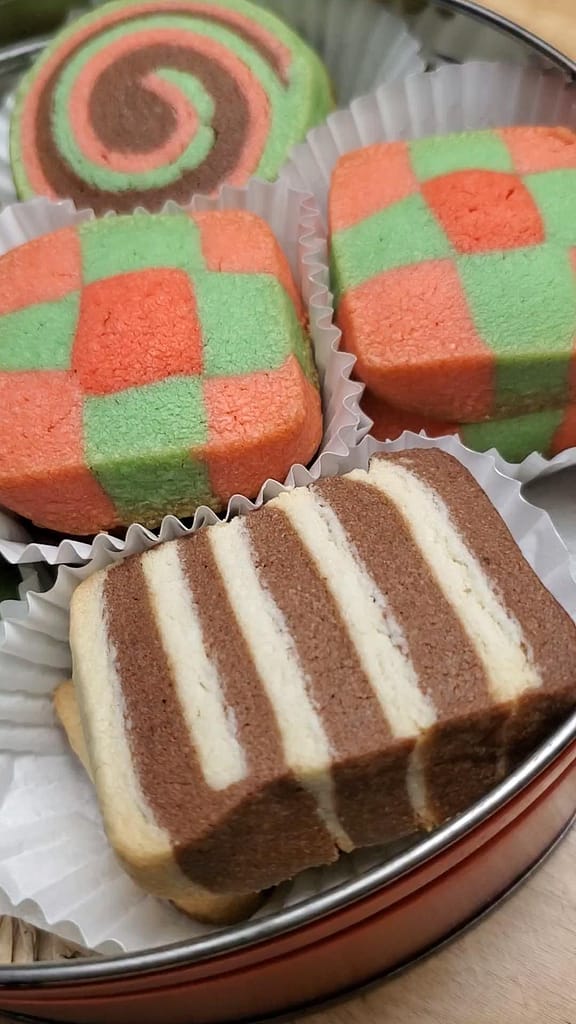 This image depicts the Christmas icebox cookies in a decorative red tin. This is a closeup image of the cookies.